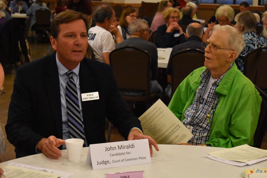 John Miraldi, a judicial candidate, speaks with a community member at Community Candidates Night.