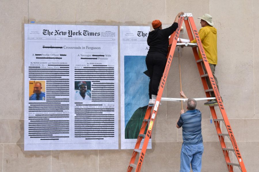 Alexandra Bell and others install “A Teenager with Promise” outside Mudd library on Tuesday, Oct. 30. The work critiques major media coverage of the 2014 fatal shooting of Michael Brown.