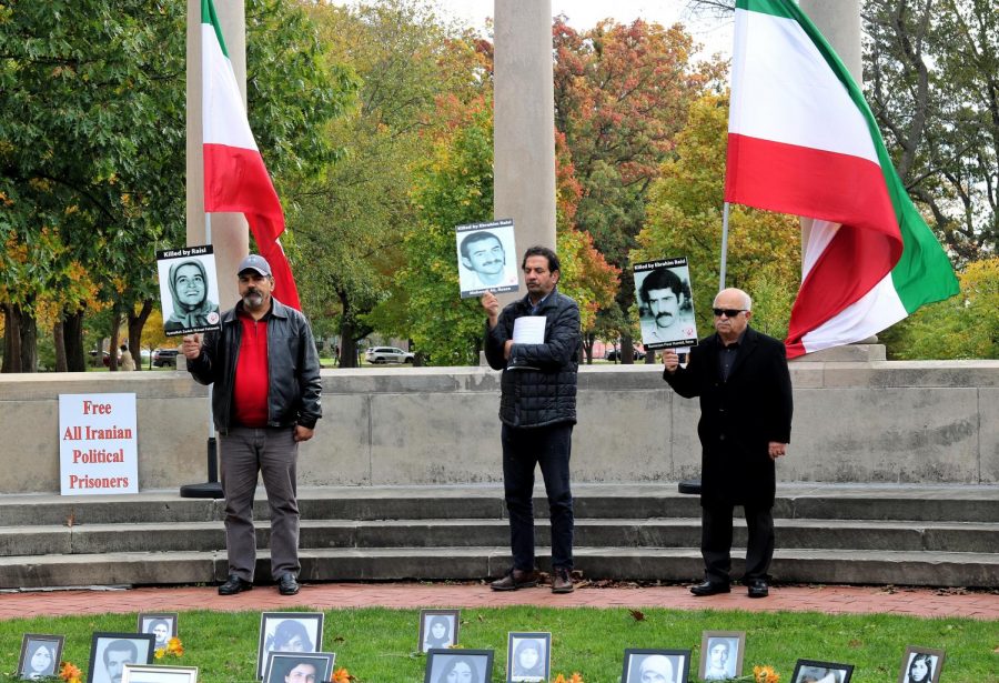 Protesters hold signs of loved ones who died in the 1988 mass killings in Iran.