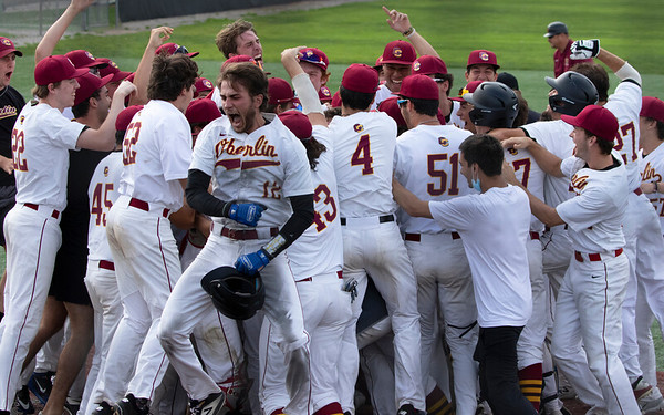 Oberlin baseball player Yianni Gardner celebrates on the field in a huddle with his team.