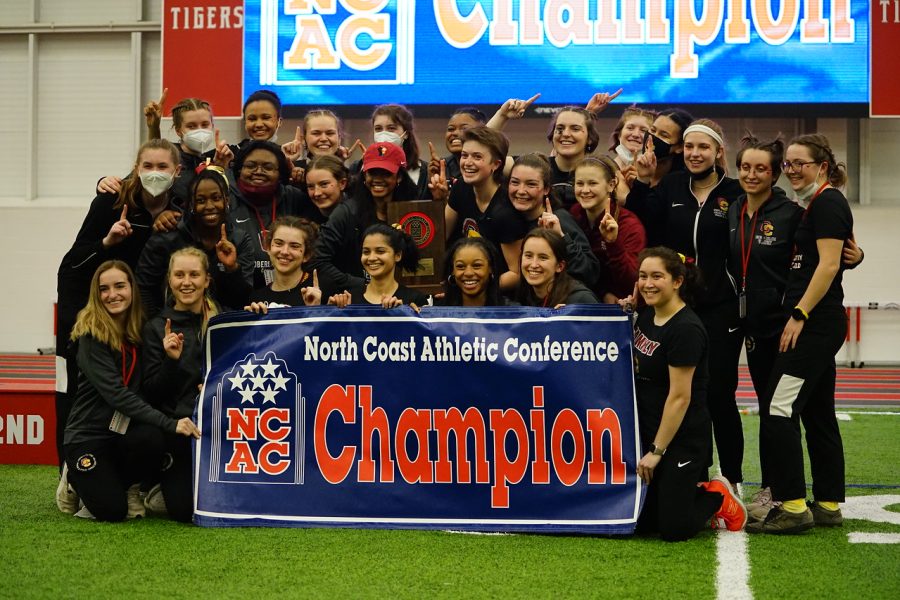 The+track+and+field+team+poses+with+the+NCAC+Championship+banner+after+winning+the+tournament.
