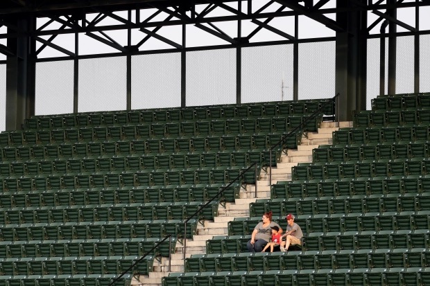A lone family sits in the otherwise empty stadium stands.