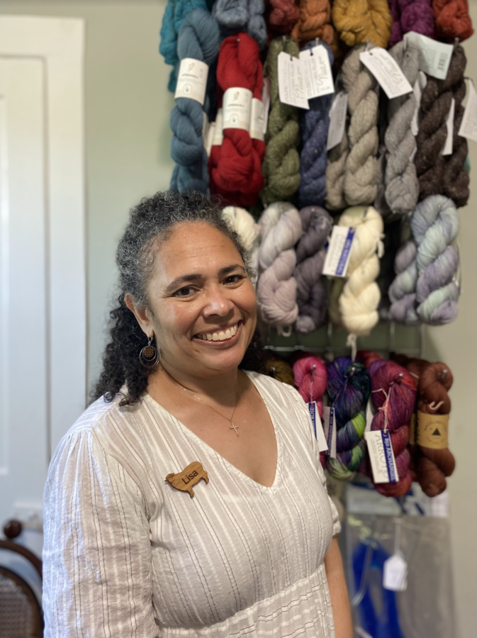 Lisa Whitfield stands in front of yarn from her store For Ewe, which fosters culturally inclusive crafting.