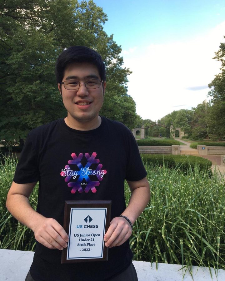 Michael Takahashi holds a plaque from a chess tournament
