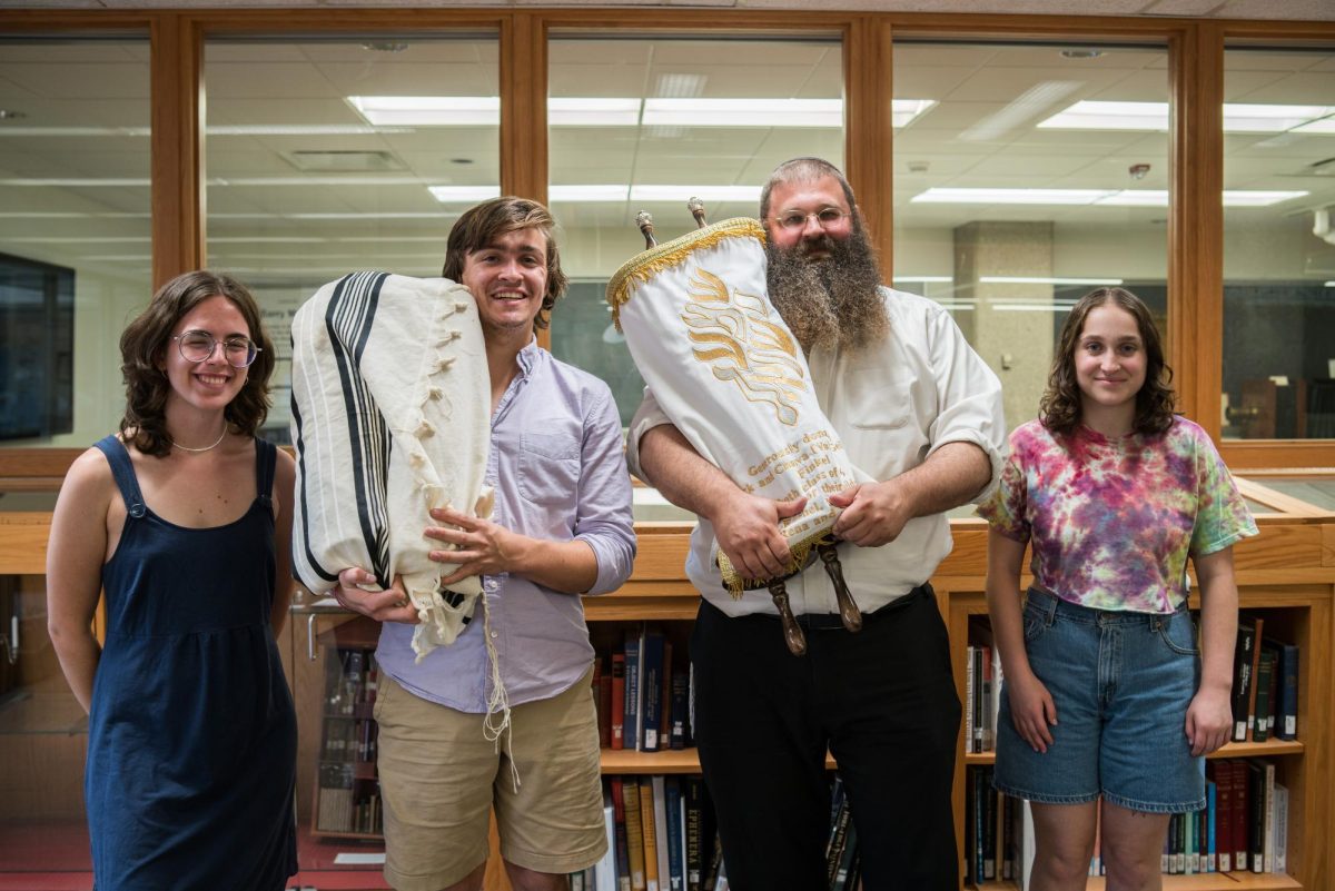 Students and Rabbi Shlomo Elkan pose with Torah scrolls. 