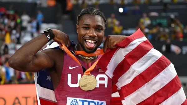 Noah Lyles holds up the American flag.